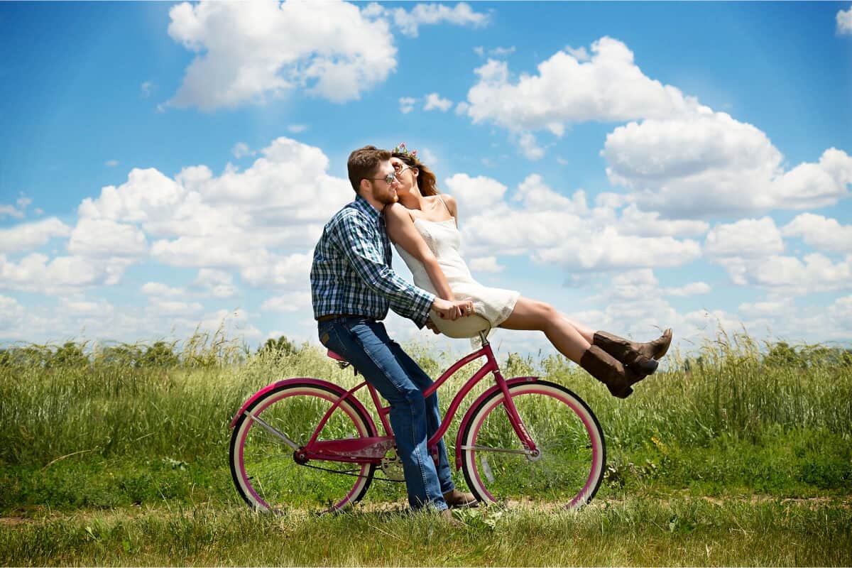 pareja montada en bici y dandose un beso
